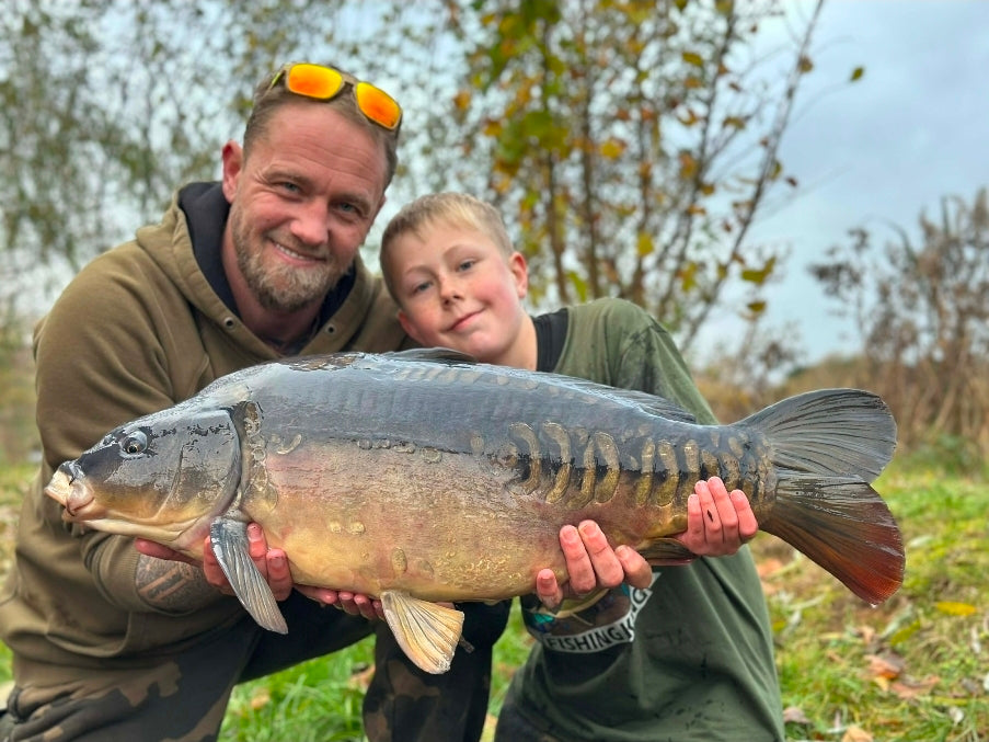 Large mirror carp held safely beside the water
